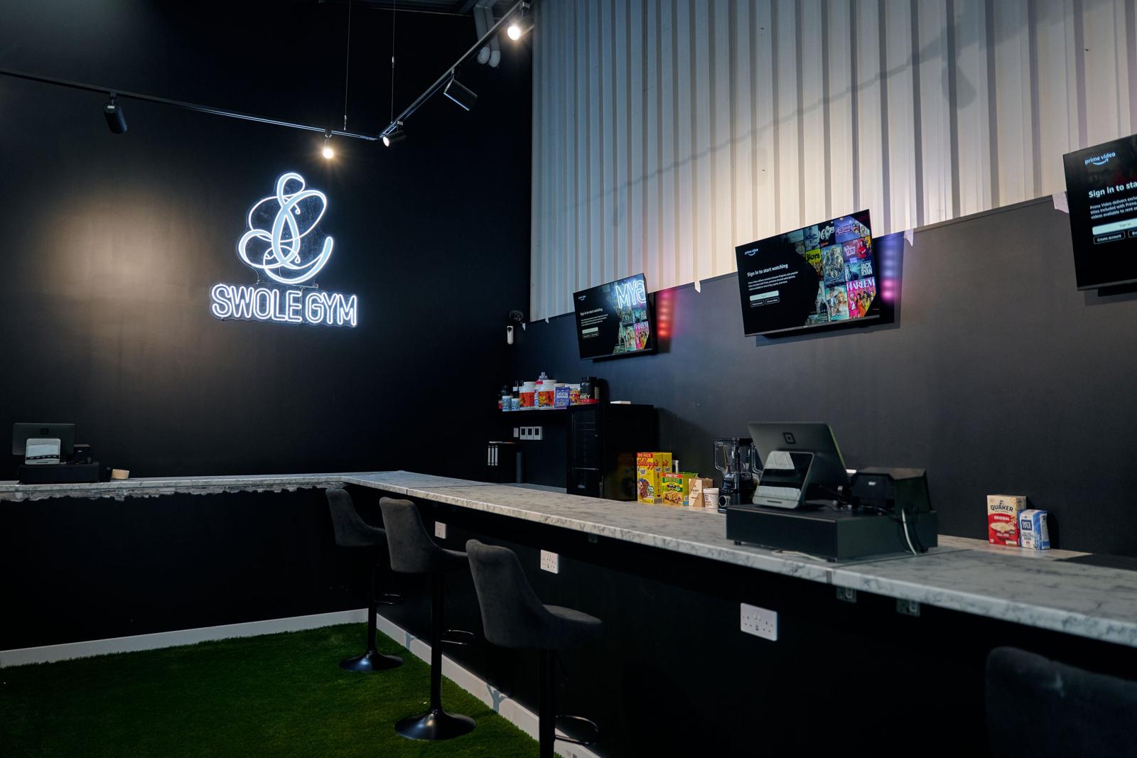 The lounge and fuel bar at Swole Gym under the neon sign